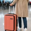 Front angle view of peach Spinny hard shell trolley bag with extended handle.